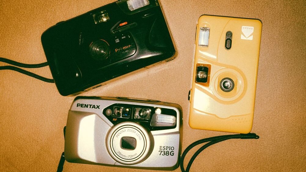 Tre fotocamere analogiche: Pentax Espio 738G, Premier PC-700 e Kodak monouso